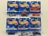 Front view of six original 1998 Hot Wheels First Editions cars in sealed retail packaging with blue background cards and blister packs showing logos and car models.