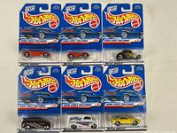 Front view showing six individually packaged Mattel Hot Wheels First Editions 1998 cars in original blister packs with blue and white packaging.