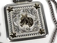 Close-up of the front of the silver pendant showing the horse head motif and star accents with detailed engraving.