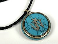 Close-up of turquoise side of round pendant showing blue stone with black veins and silver symbol.