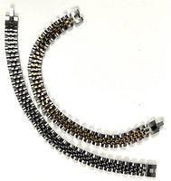Two stainless steel bracelets, one silver colored and one silver with gold accents, laid flat showing full length and clasp on a white background.