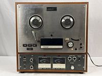 Front view of the vintage TEAC A4000 tape recorder with wood side panels and metal front, showing large reels, control switches, and dual VU meters.