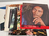 Top view of vintage vinyl albums with Bob Marley Legend prominently shown, and partial view of other albums underneath including Kenny Rogers and other artists.