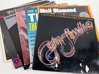 Eight vintage vinyl LP albums arranged side by side showing front covers from artists including Neil Diamond, Captain & Tenille, Eagles, and The Ventures.