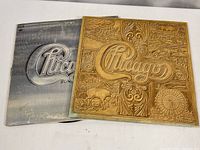 Two vintage Chicago double vinyl albums with their covers visible; one golden embossed cover and one silver logo cover.