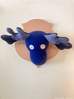 Front view of plush moose head on wood plaque