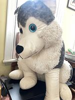 Front view of large grey and white plush wolf stuffed animal on chair