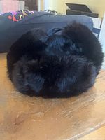 Front view of black fur ushanka hat showing dense fur and ear flaps
