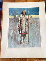 Portrait print of Indigenous man in white embroidered coat holding spear, teepees in background