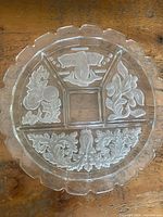Full view of round divided glass platter showing five compartments and etched motifs