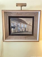 Full view of framed painting with picture light attached