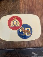 Front view of RCMP 50th Anniversary buckle showing crest, dog silhouette, dates