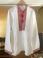 Full front view of white embroidered shirt on hanger