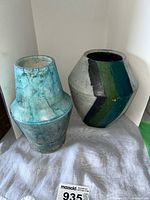 Photo showing two pottery vases side by side: one light blue mottled vase and one blue/green striped vase