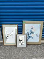 Three framed Asian themed artworks against blue industrial door background.