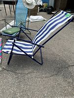 Blue and white wide striped folding beach chair with blue metal frame, reclined position