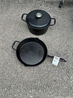 Cast iron pot with lid and 12-inch cast iron skillet placed on ground, showing top views of both items.