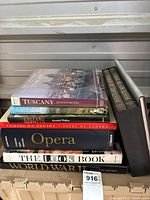 Stack of large hardcover coffee table books on various subjects including travel, art history, opera, and war history.