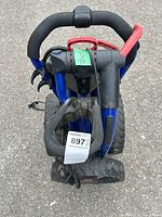 Top view folded golf caddy showing black foam handle and red locking mechanisms on blue metal frame with three wheels.