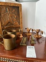 Copper candlesticks, copper mugs, small brass items, abacus, and horse relief panel on table