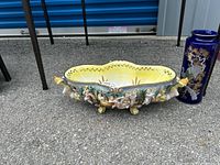 Ornate Capodimonte Italian porcelain centrepiece bowl with cherub and floral decorations, yellow interior, and multiple feet with gold accents.