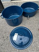 Full lot showing large blue enamelware pot, strainer insert, and lid laid on ground.