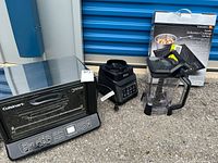 Cuisinart convection oven toaster broiler, Ninja blender, and Kurig induction cooktop with box visible outdoors on pavement.