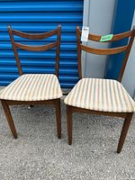 Pair of mid-century modern style wooden dining chairs, showing front view and seat upholstery