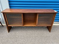Front view of the mid century modern display cabinet showing two sliding glass doors and center compartment.