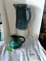 Photo showing the tall pottery pitcher and smaller creamer side by side on a white cloth background
