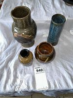 Overhead view of four pottery vases on a white cloth showing color and glaze details