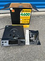 Kodak Carousel 4600 slide projector placed in front of its original cardboard box and a white slide tray and user guide beside it.