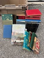Photo of assorted vintage books in various sizes, covers, and colors, arranged on the ground.