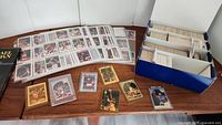 Photo of multiple basketball cards laid out on a wooden table including loose cards and a box full of cards separated by dividers.