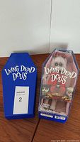Living Dead Doll Violet in original coffin-shaped box with blue outer sleeve that reads 'Living Dead Dolls'.