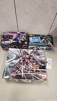 Three Bandai Gundam model kits boxed and assembled as-is, shown on a flat surface.