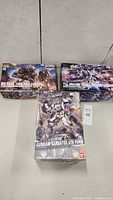 Three boxed Bandai Gundam model kits including 1:100 Gundam Barbatos 6th Form and two 1:144 scale kits - Amazing Strike Freedom Gundam and MS-06CK Zaku Half Cannon.