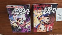 Two Corpse Party manga volumes 1 and 4 shown side by side on a wooden surface.