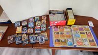 Overall lot on table showing booster pack wrappers, storage tins, binder