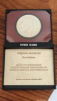 Full view of coin in black display case with text card describing the coin as a sterling silver $25 proof edition commemorating the 25th wedding anniversary of Queen Elizabeth II and Prince Philip, struck at the Royal Canadian Mint.