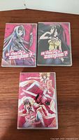 Three Funimation DVD cases from 'Is This a Zombie?' with anime art characters lying on wooden surface