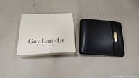 White Guy Laroche Paris branded box and black leather wallet side by side.