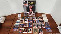 Full view of Michael Jordan hardcover collector book with multiple basketball cards spread on wooden surface.