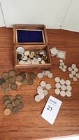 Wooden box open, coins inside and spread on table