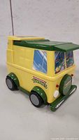 Front and side angle of yellow and green plastic van with TMNT window decals and logos, showing overall design and condition.