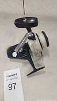 Side profile of vintage Zebco Cardinal #7 fishing reel showing handle, spool, and drag knob.