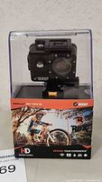 Front view of Wasp Cam Rox HD action camera in clear plastic packaging with product graphics showing a mountain biker and branding.