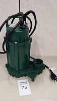Full view of green Zoeller submersible sump pump with power cord coiled on top.