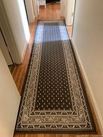 Full view of the gray and white patterned runner rug laid out in a hallway on hardwood floor.