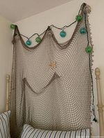 Decorative fishnet draped on wall with green and blue globe string lights attached.